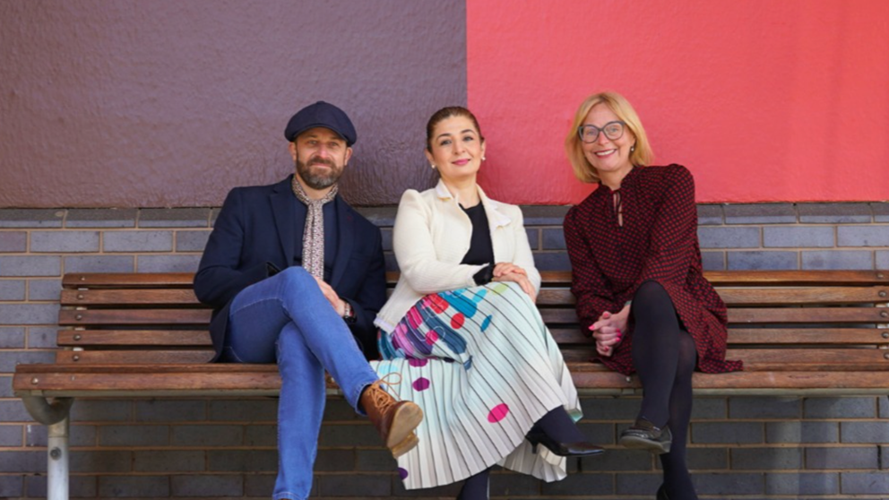 An image of three people sat on a bench in front of a wall that has colour swatches from the 'Solihull colour palette'